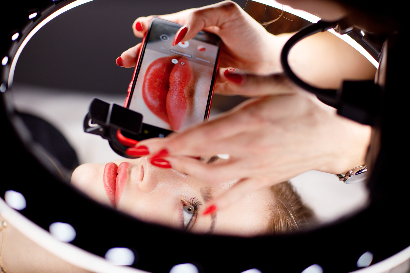 Cosmetologist Making Photo of Work on Mobile Phone Red Permanent Make up Tattoo on Young Woman Lips